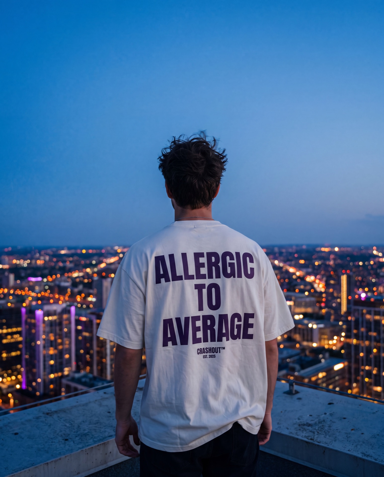 Model on a rooftop at blue hour over the city skyline wearing an Allergic To Average tee